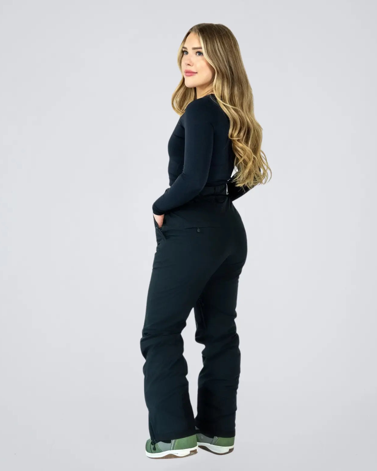 Back view of Nexarina Avani Snow Pant in Classic Black, hands in pockets.