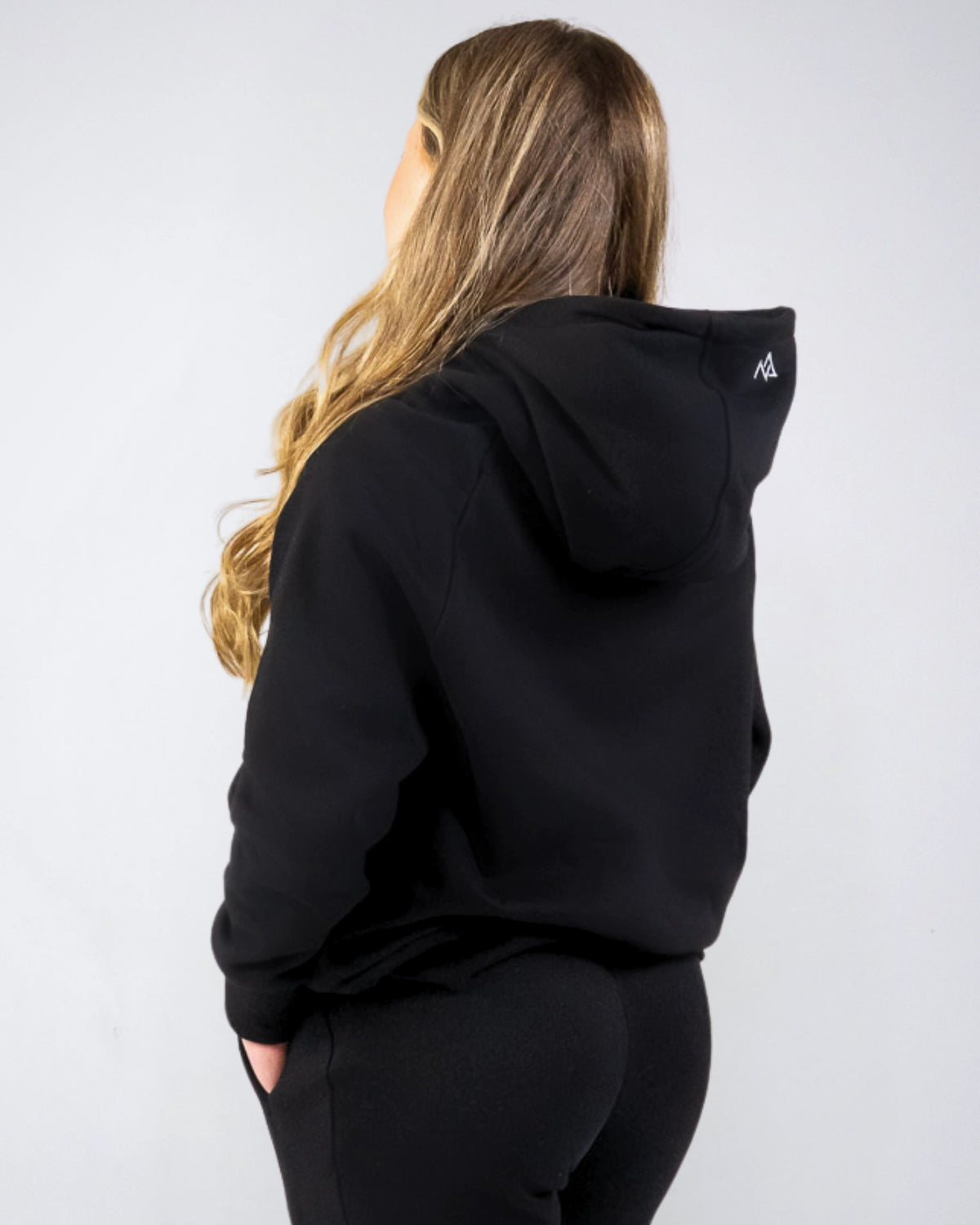 Back angled view of the women's Everly Hoodie in Midnight Black showing the hood shape and relaxed fit.