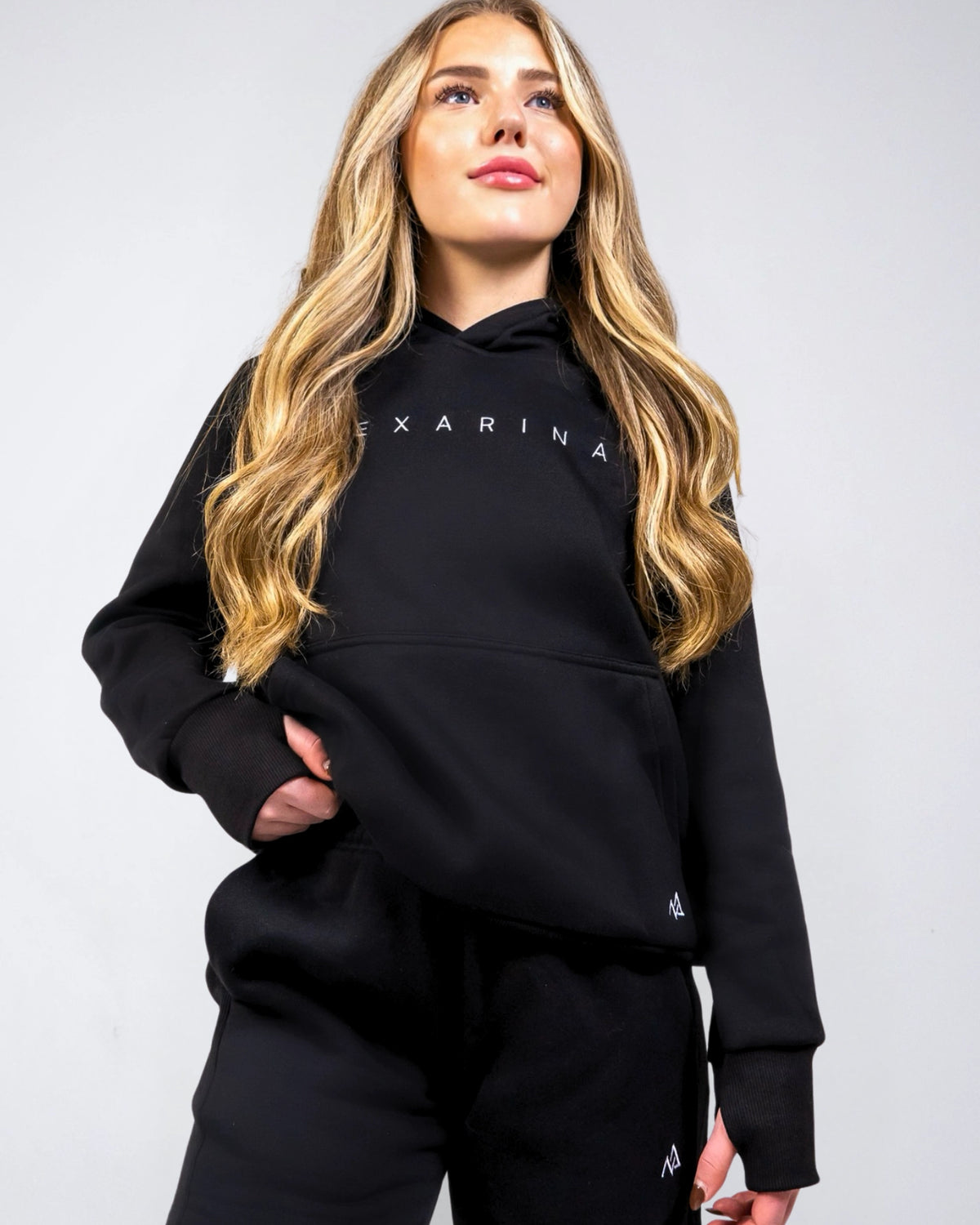 Front view of the women's Everly Hoodie in Midnight Black showing the relaxed fit, ribbed cuffs and Nexarina logo.