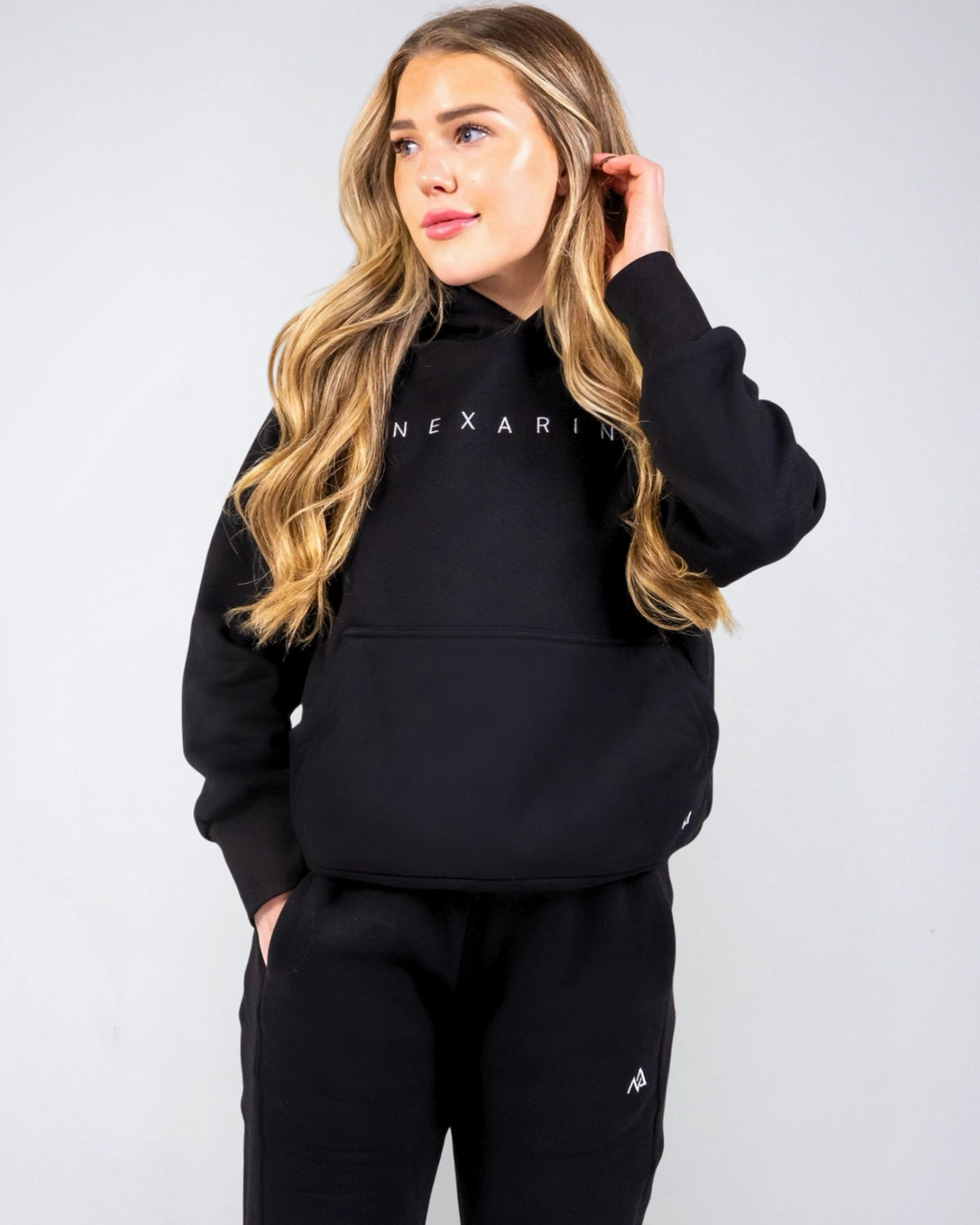 Front view of the women's Everly Hoodie in Midnight Black showing the Nexarina chest logo and kangaroo pocket.