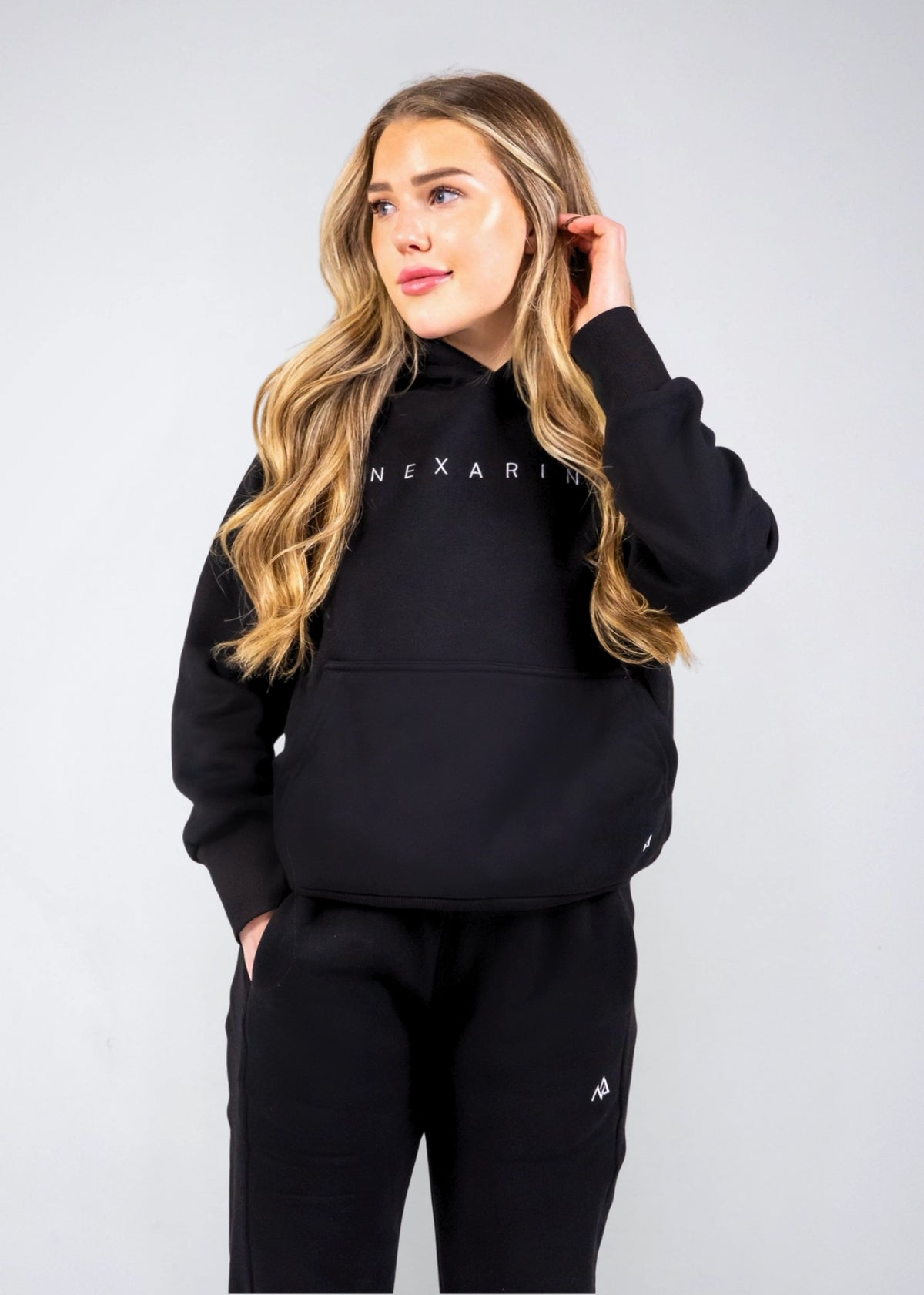 Front view of the women's Everly Hoodie in Midnight Black showing the Nexarina chest logo and kangaroo pocket.