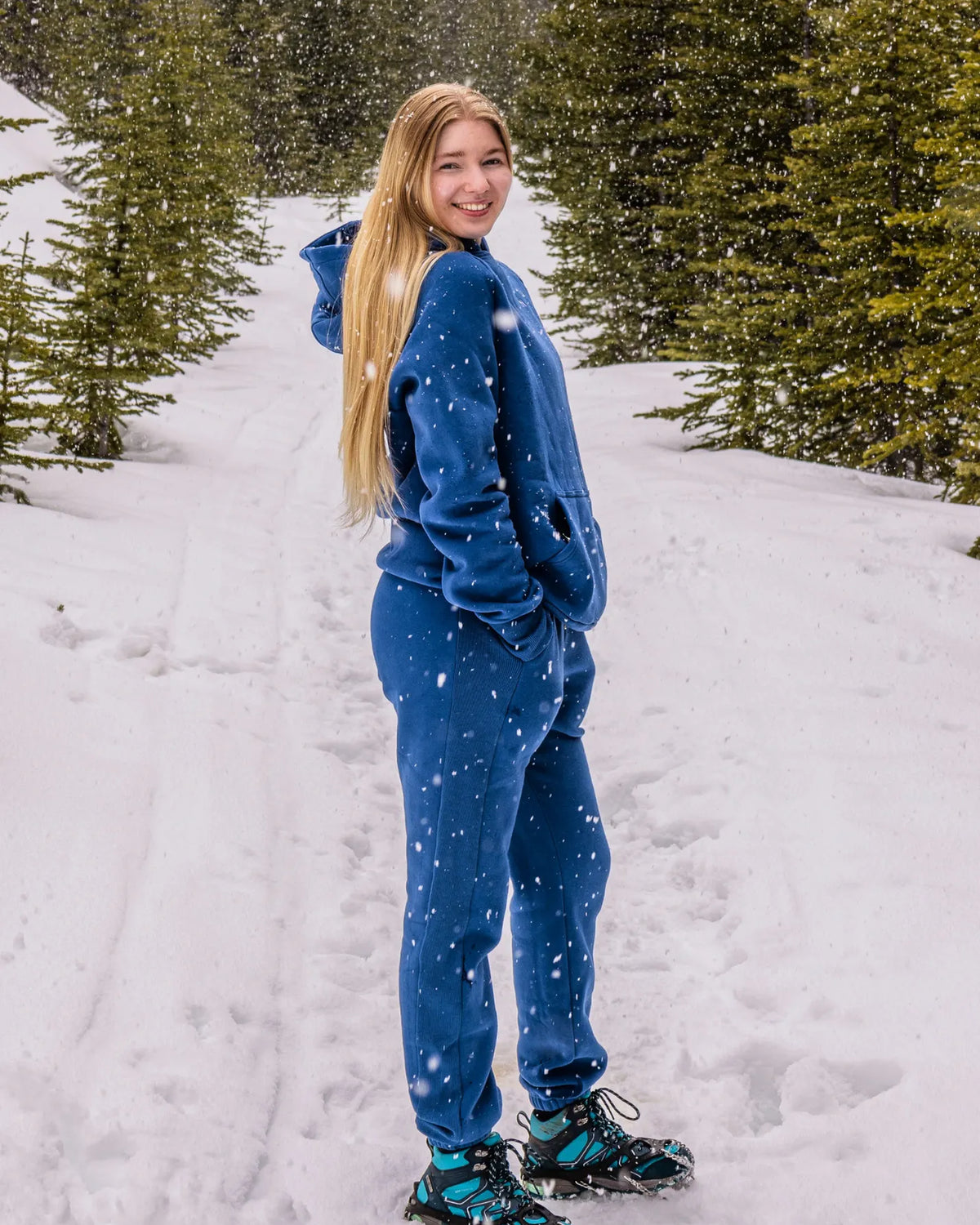 Women's Everly Hoodie in Dusty Blue worn with matching sweatpants in a snowy mountain setting.