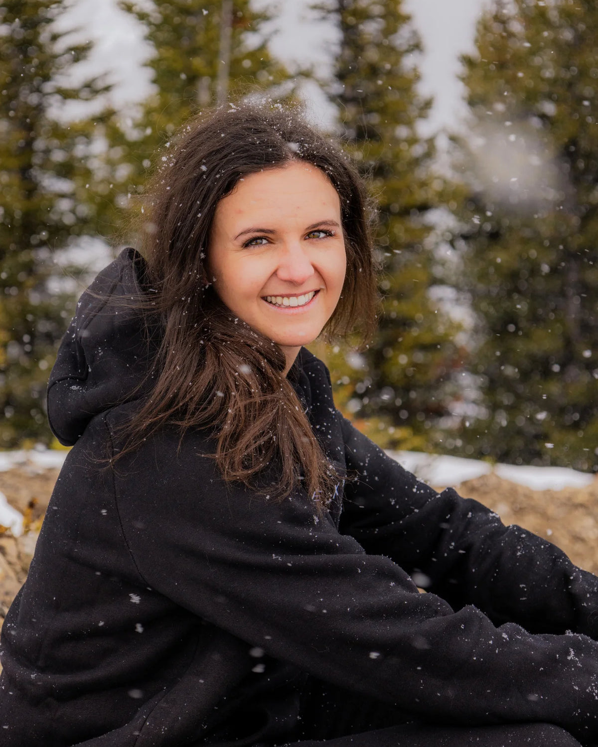 Women's Everly Hoodie in Midnight Black worn outdoors in falling snow.