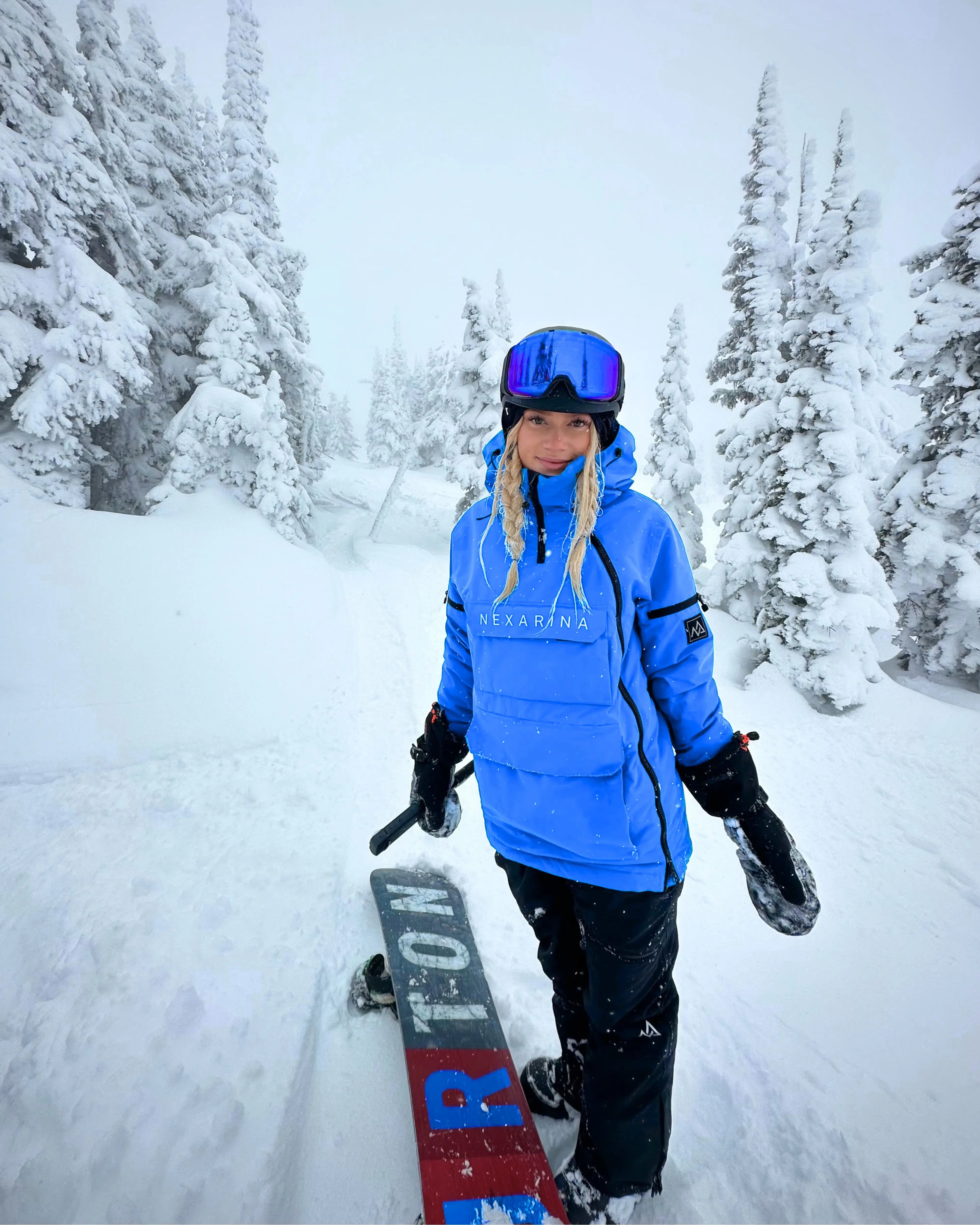 Woman snowboarding in Nexarina Indy Jacket - Arctic Blue waterproof outerwear.