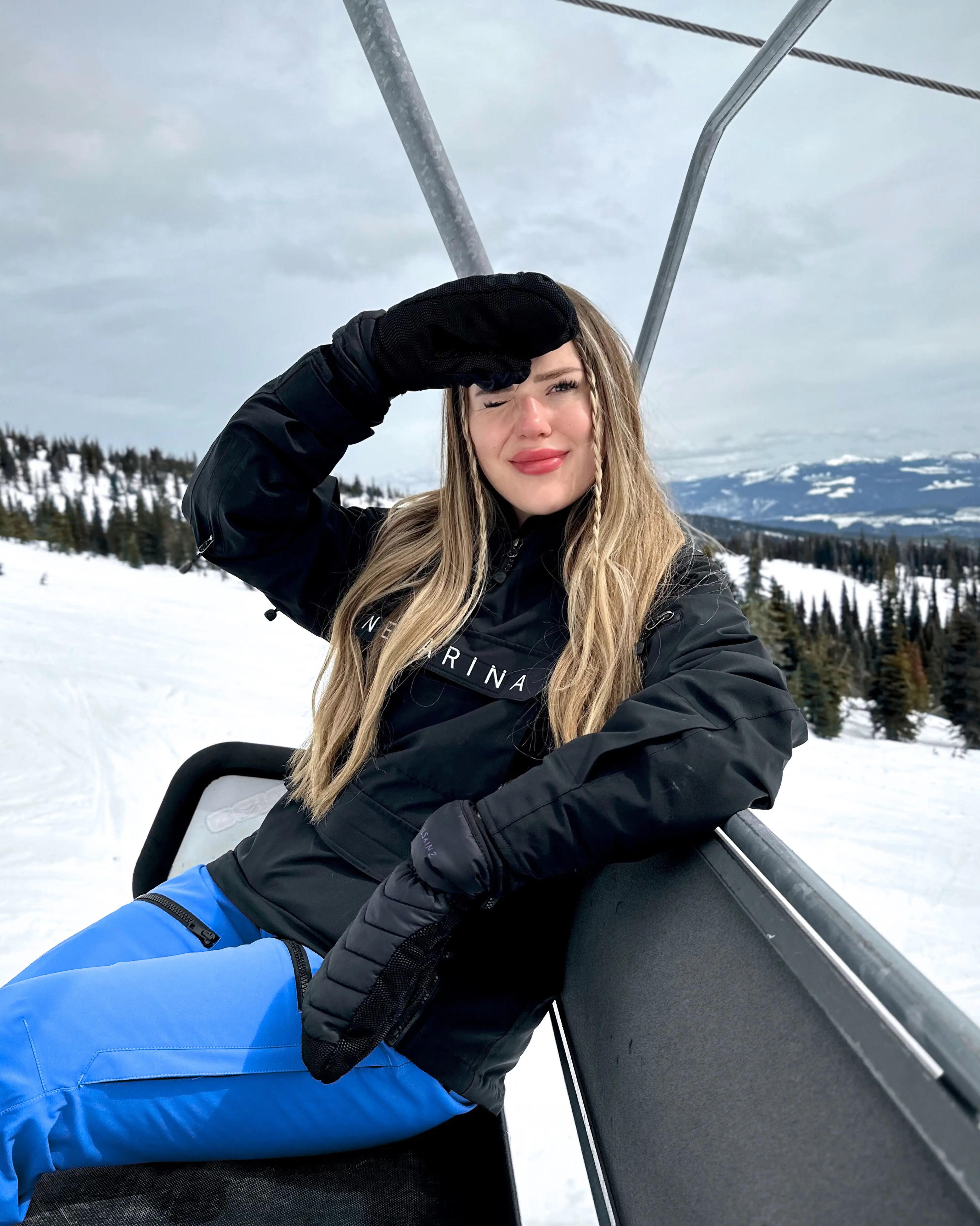 Woman on chairlift in Nexarina Avani Snow Pants - Arctic Blue women’s mountain outerwear.