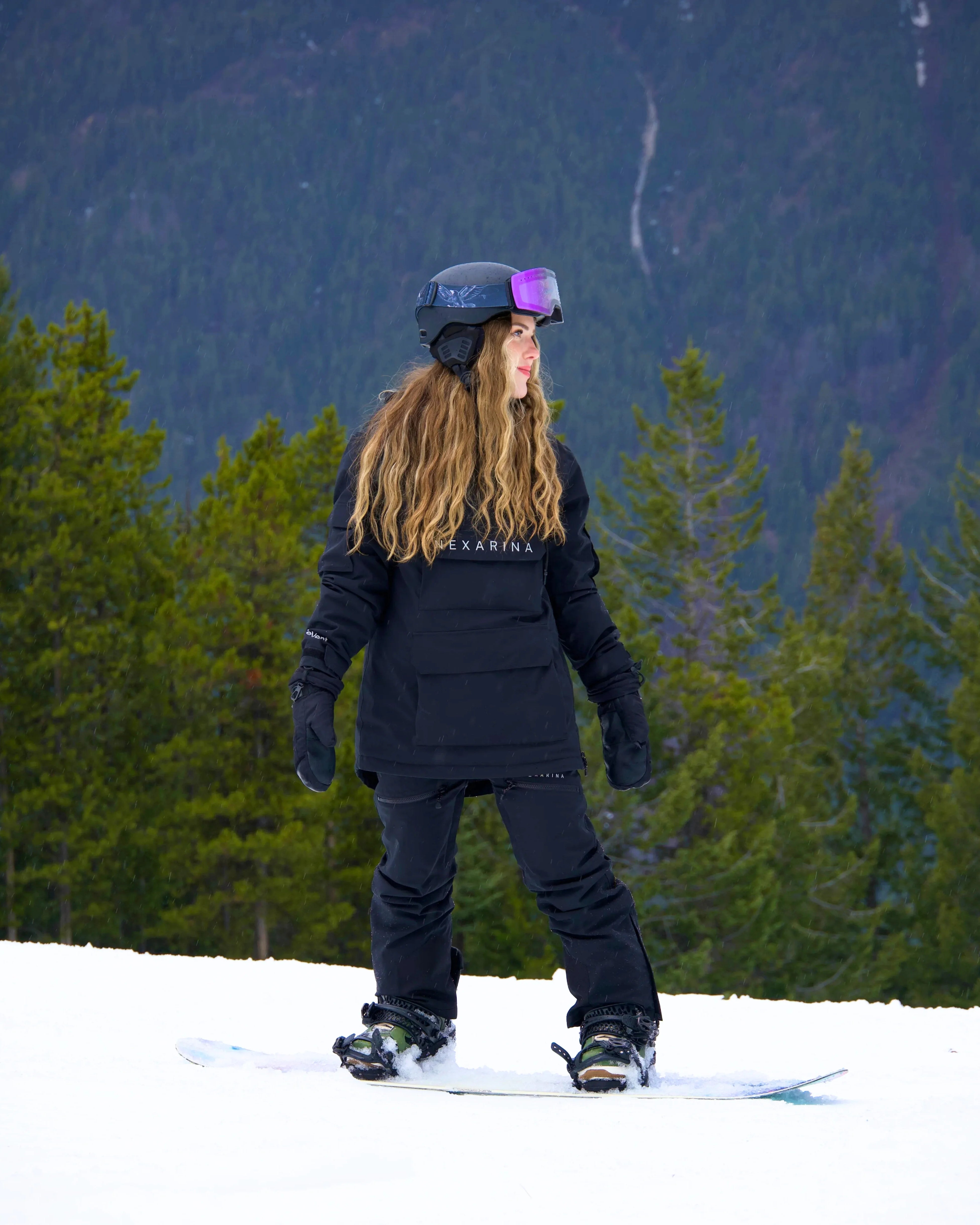 Snowboarder wearing Nexarina black Avani Snow Pant riding on a snowy mountain.