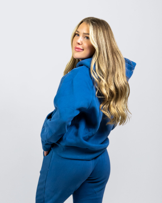 Woman wearing Nexarina Dusty Blue Hoodie smiling and looking back.