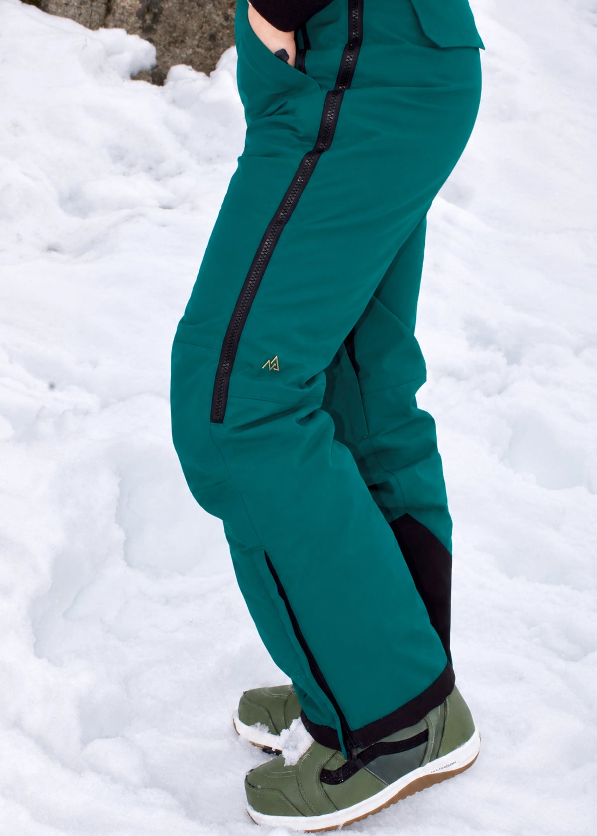 Side view of Nexarina Everette Emerald Green women's snow bibs showing the articulated knee fit.