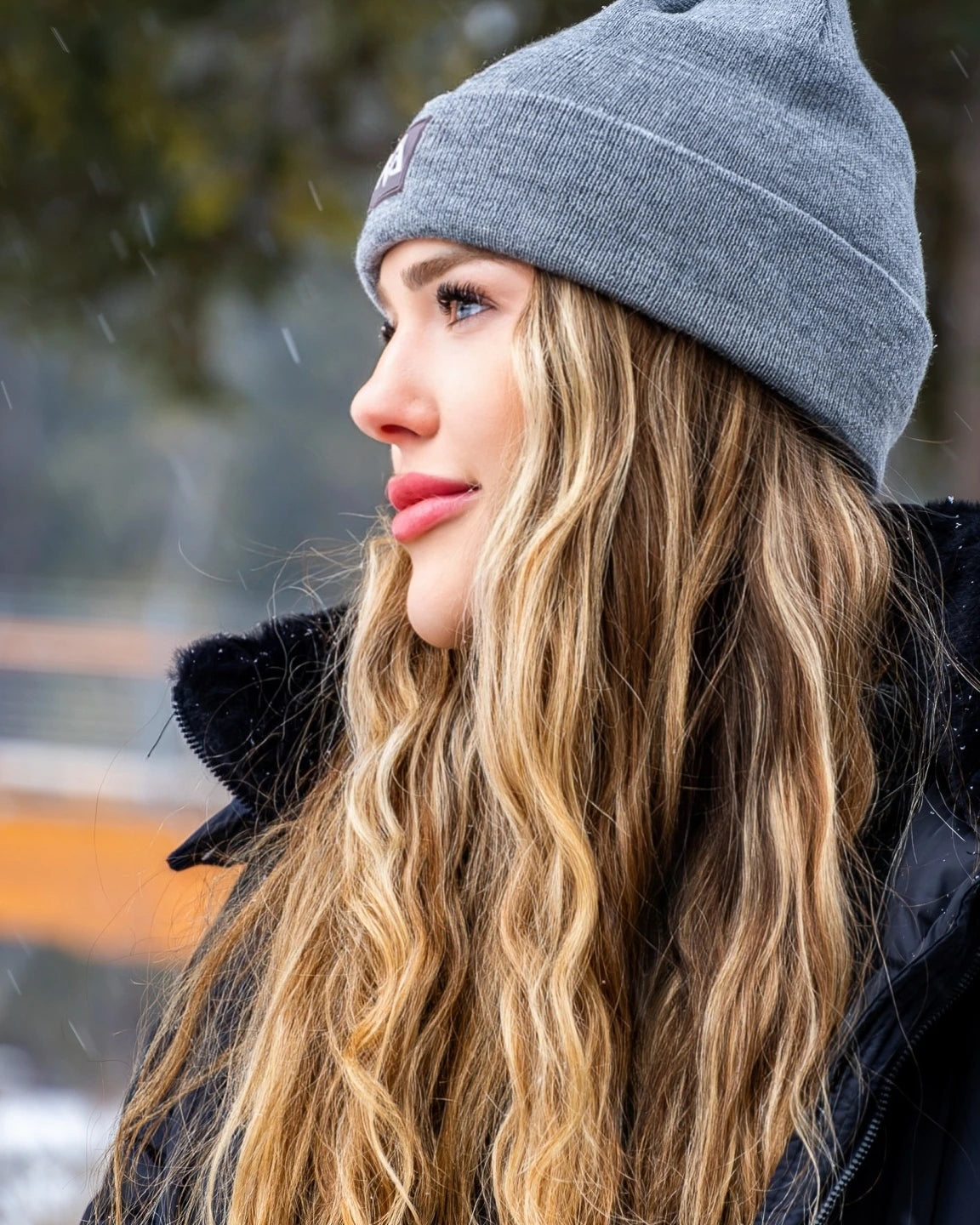 Woman in a grey Nexarina beanie looking off to the side.