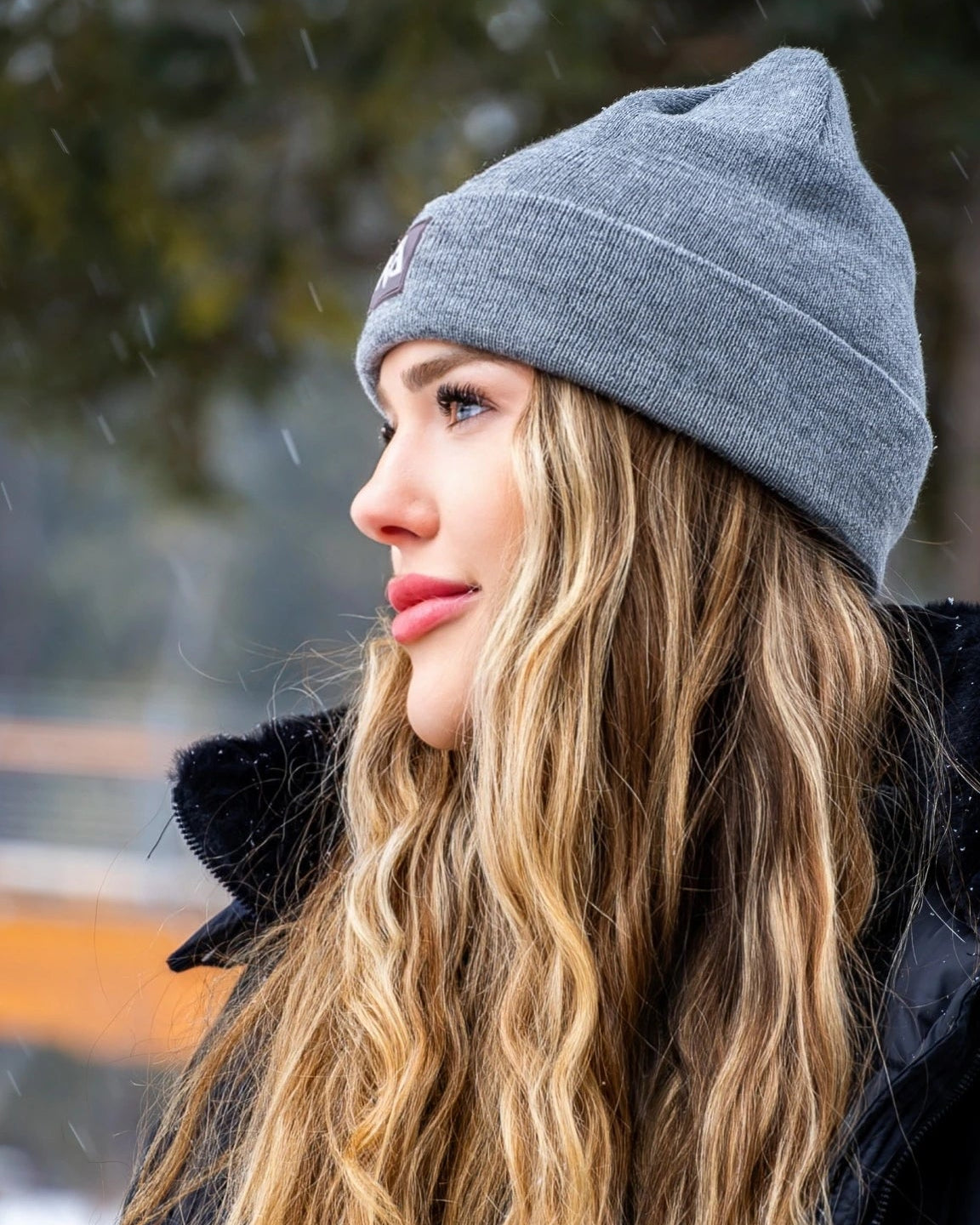 Woman in a grey Nexarina beanie looking off to the side.