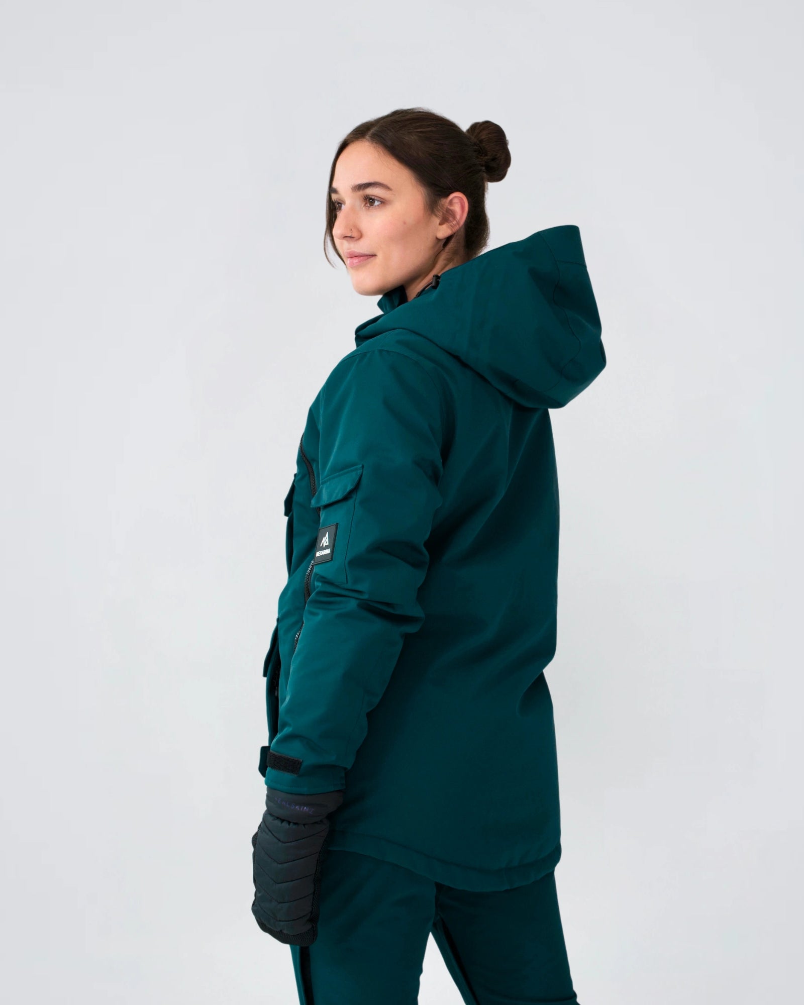 Back view of woman wearing Nexarina Indy snow jacket in emerald green, studio shot