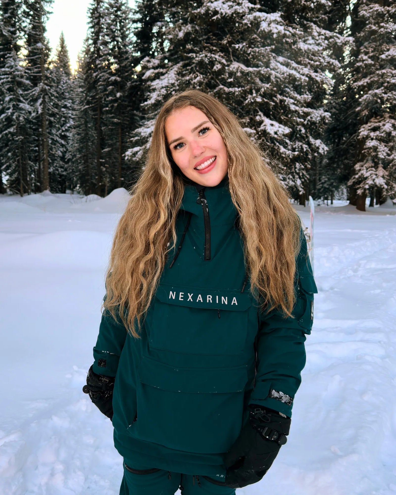 Woman wearing Nexarina Indy snow jacket in emerald green, front view outdoors