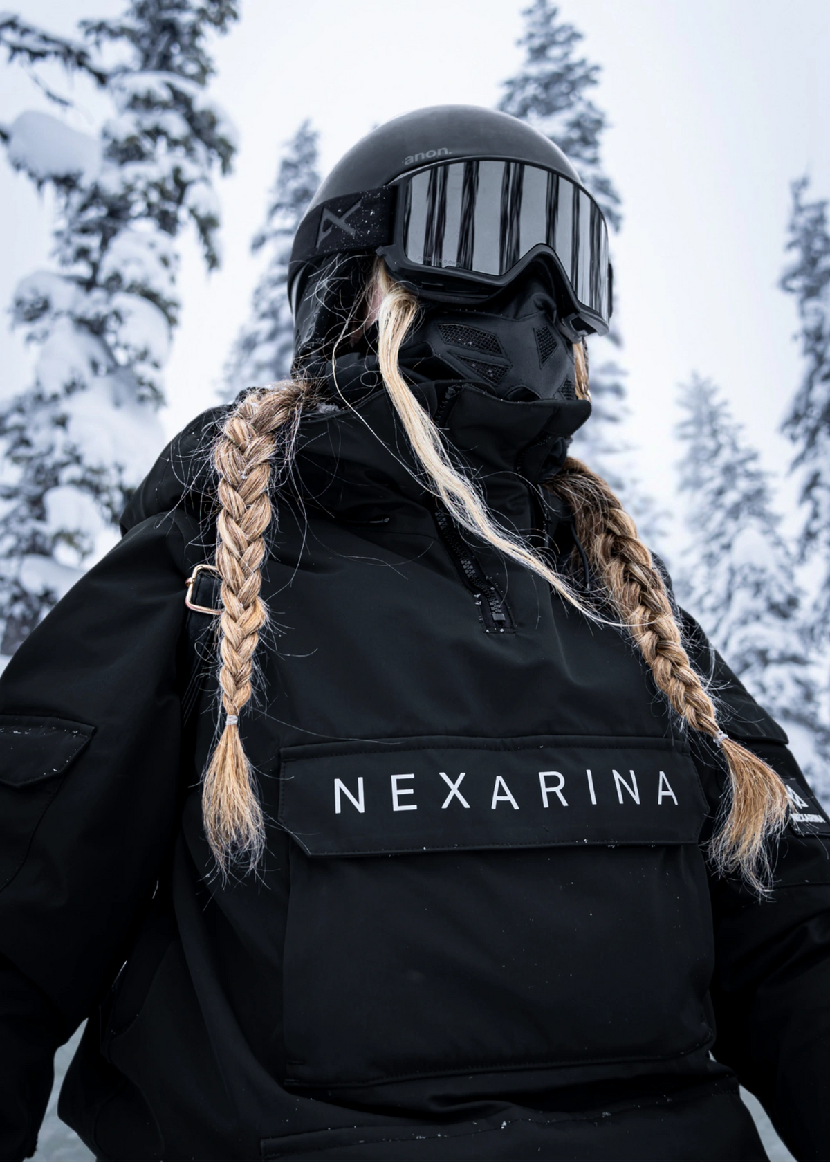 Person wearing a black jacket with 'Nexarina' branding in a snowy forest setting