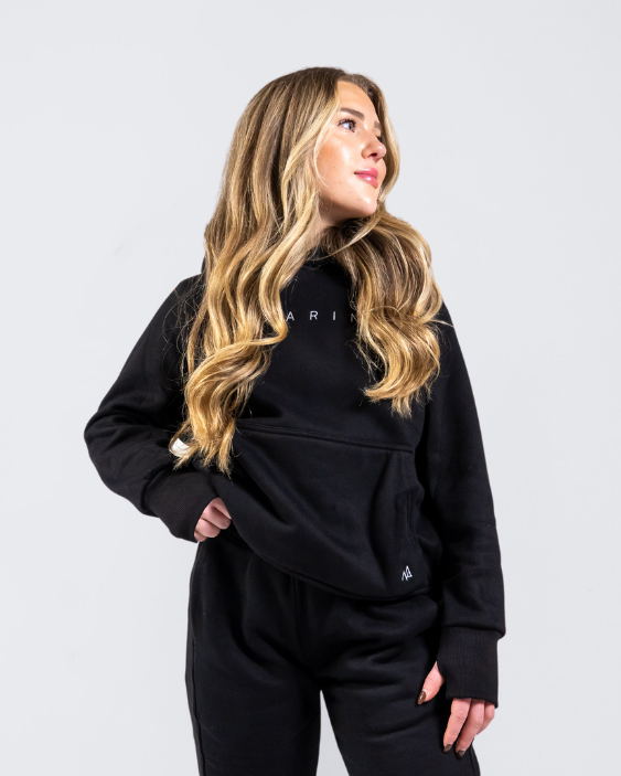 Woman in Nexarina Midnight Black Hoodie smiling and looking sideways.