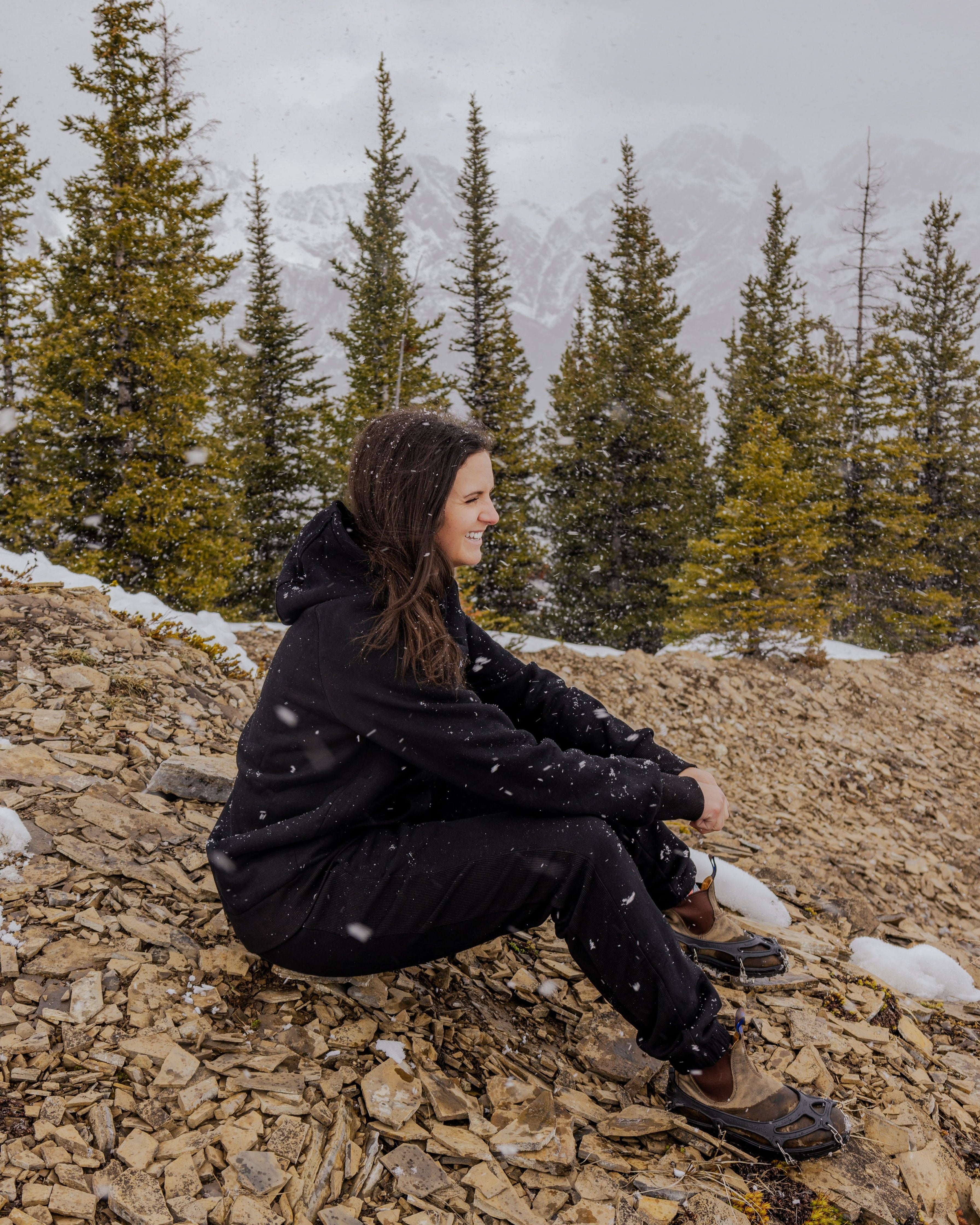 Woman wearing Nexarina Midnight Black Hoodie sitting on a mountain.