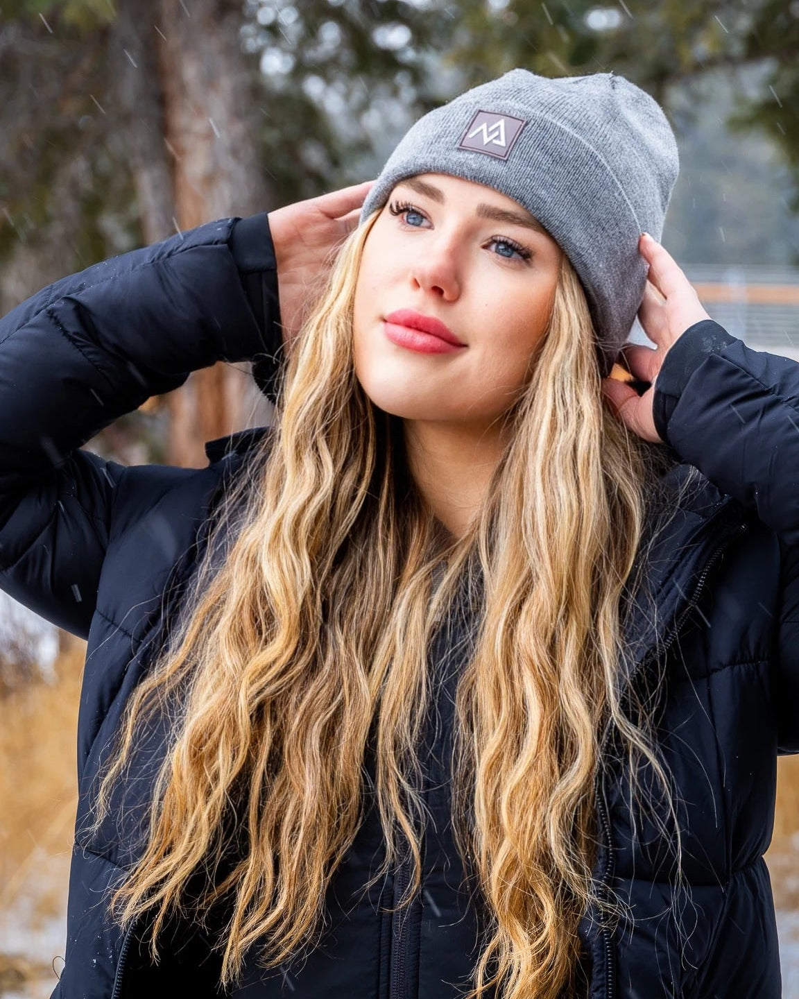 Profile view of a young woman in a grey beanie by Nexarina, gazing into the distance, amidst falling snow.