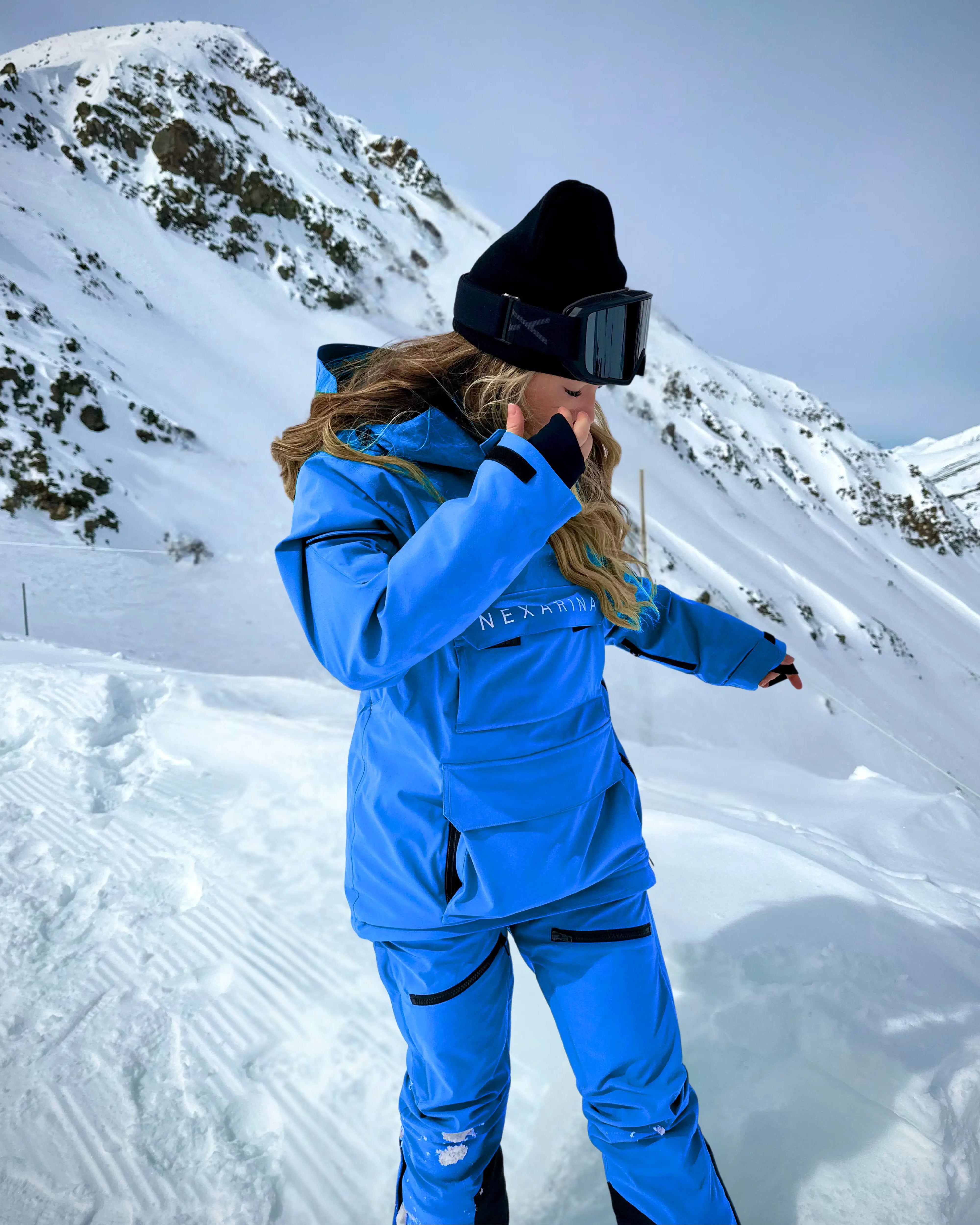 A snowboarder wears blue Avani snow pants, designed for movement, warmth, and protection in winter conditions.
