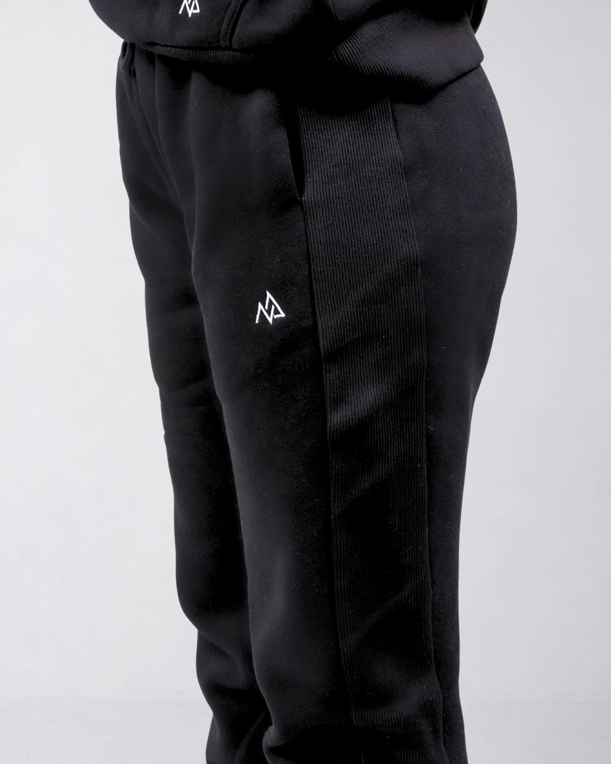 Close-up of the Nexarina logo and ribbed side panel on black sweatpants