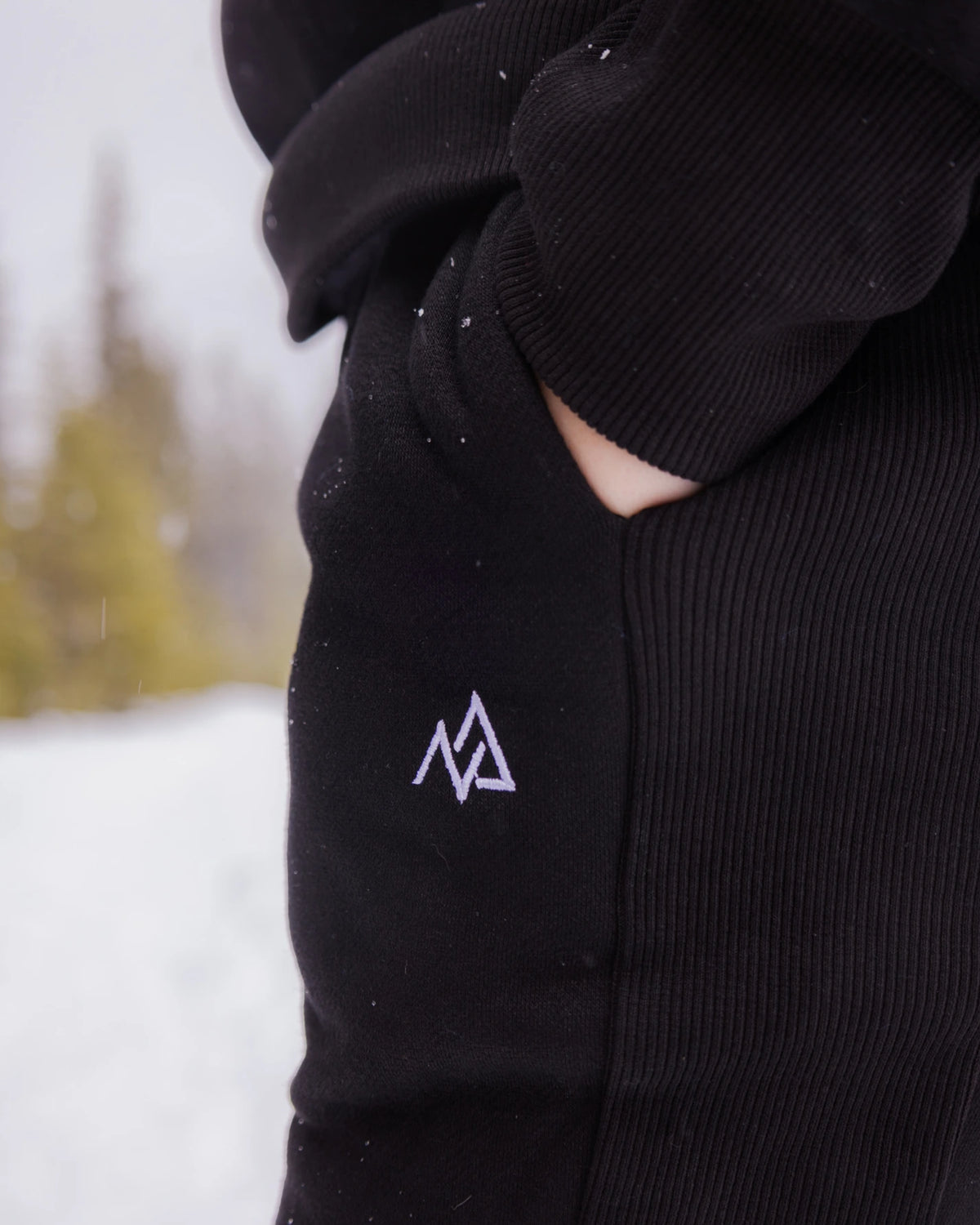 Close-up of the Nexarina logo and ribbed side panel on Midnight Black Willow Sweatpants