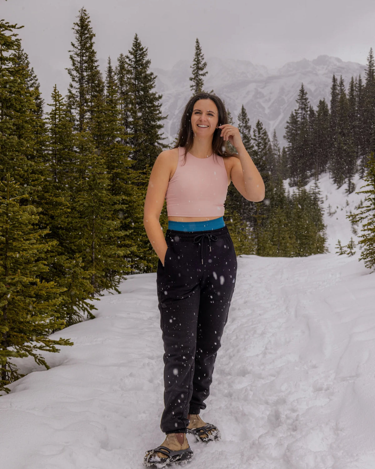 Woman wearing Nexarina Willow Sweatpants in Midnight Black on a snowy mountain trail