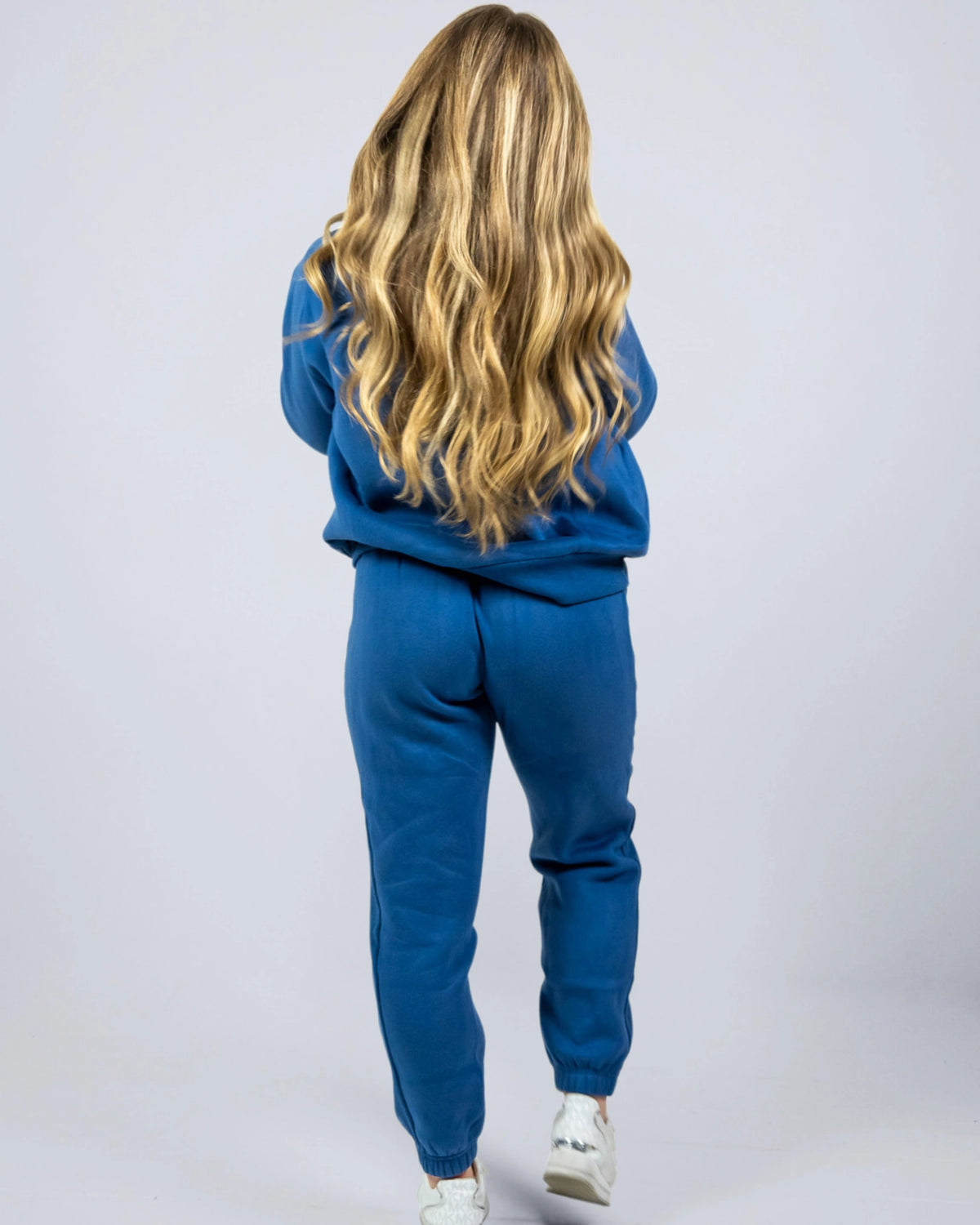 Women's Willow Sweatpants in Dusty Blue shown from the back while walking in a matching blue hoodie.