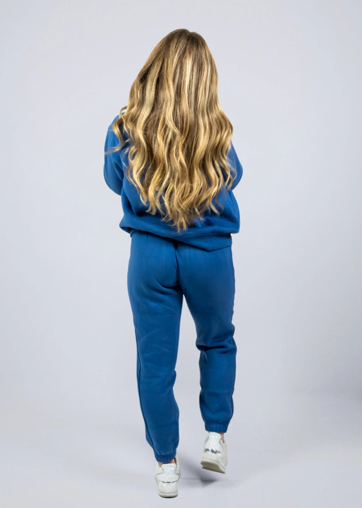 Women's Willow Sweatpants in Dusty Blue shown from the back while walking in a matching blue hoodie.