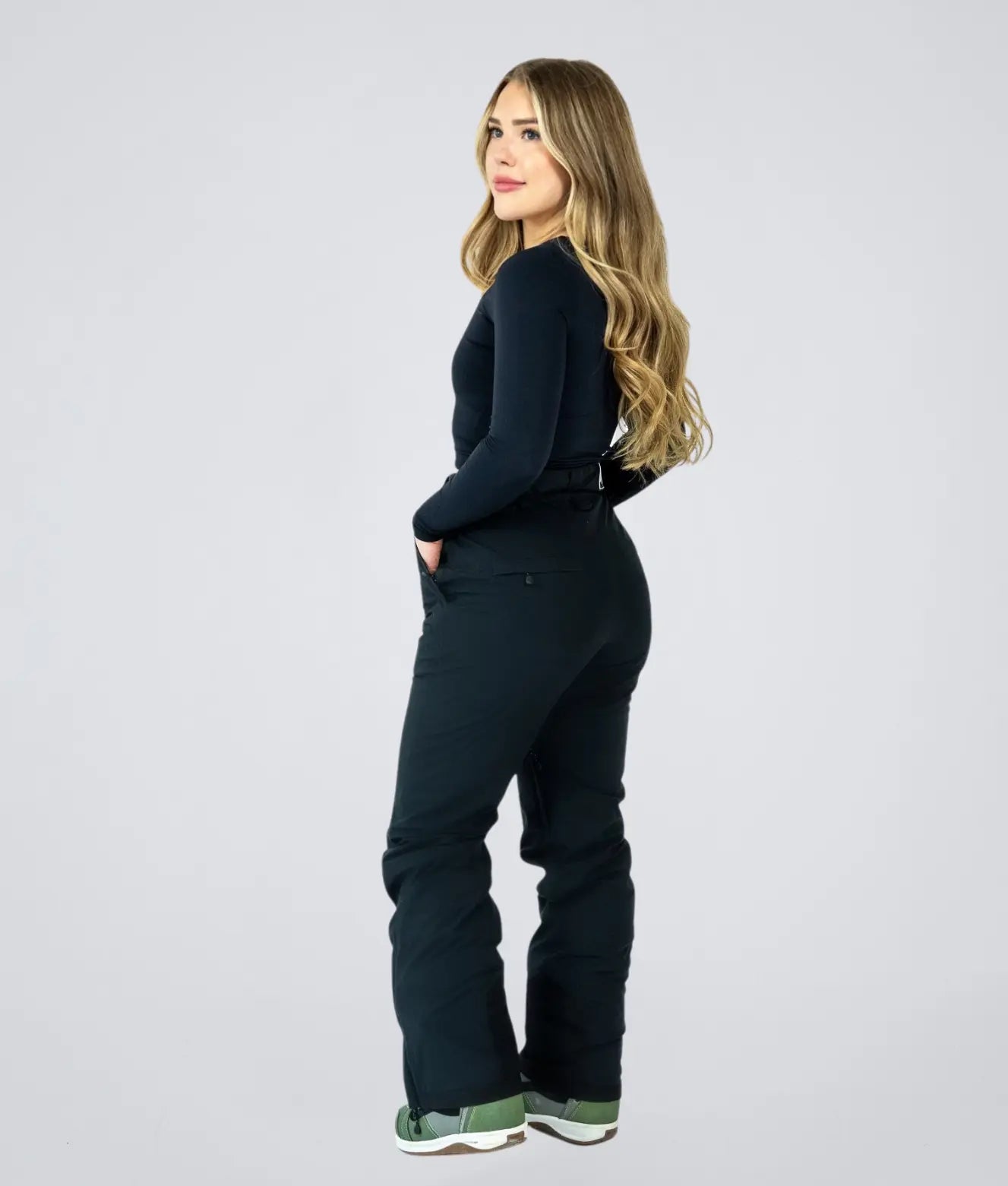 Back view of Nexarina Avani Snow Pant in Classic Black, hands in pockets.