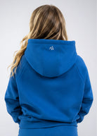 Back view of the Nexarina Everly Hoodie in Dusty Blue showing the hood and back logo