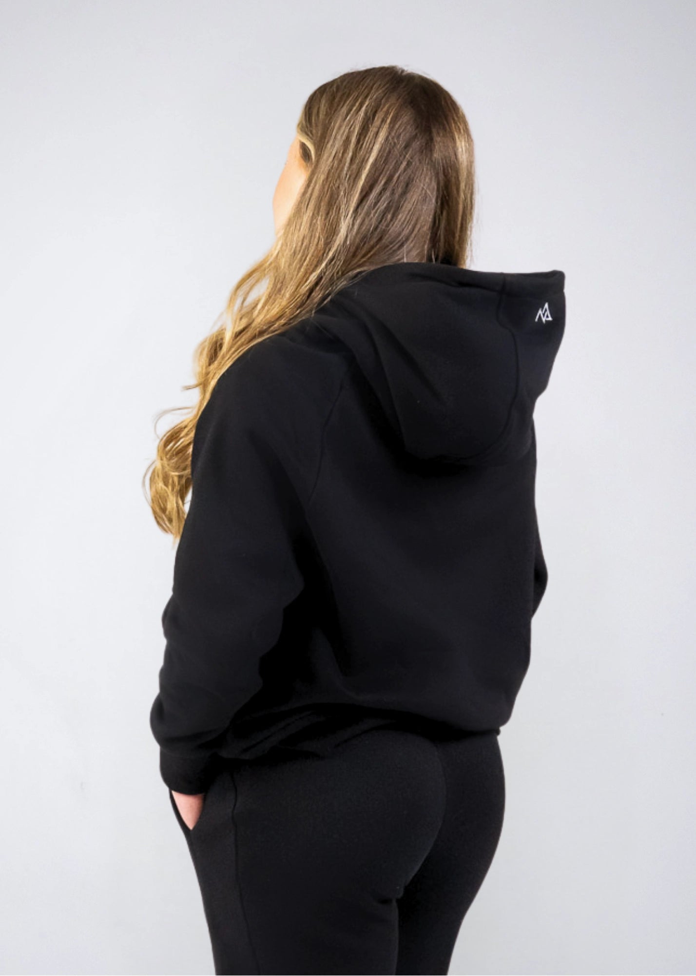 Back angled view of the women's Everly Hoodie in Midnight Black showing the hood shape and relaxed fit.