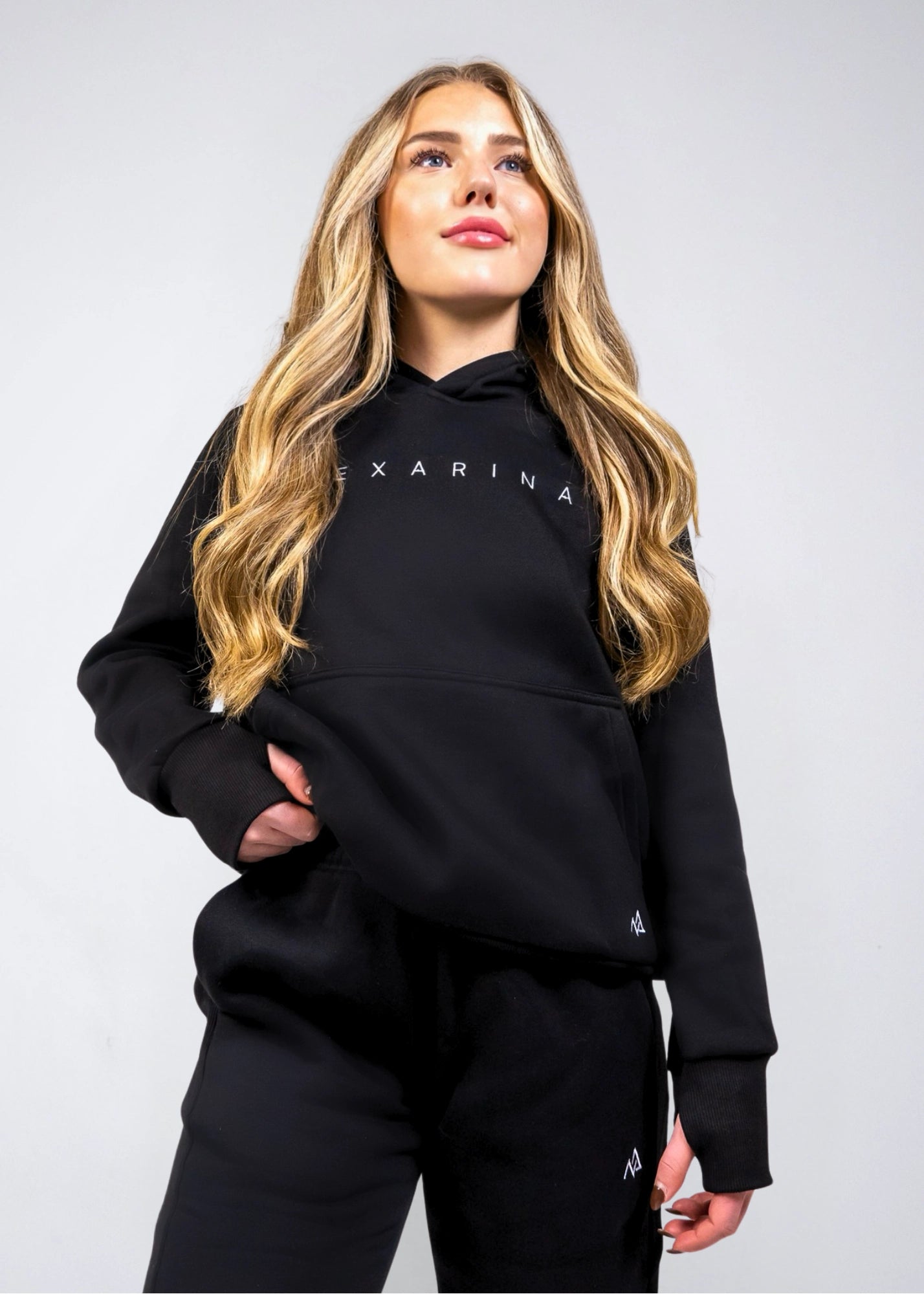 Front view of the women's Everly Hoodie in Midnight Black showing the relaxed fit, ribbed cuffs and Nexarina logo.