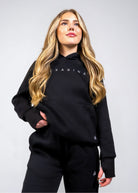 Front view of the women's Everly Hoodie in Midnight Black showing the relaxed fit, ribbed cuffs and Nexarina logo.