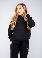 Front view of the women's Everly Hoodie in Midnight Black showing the Nexarina chest logo and kangaroo pocket.
