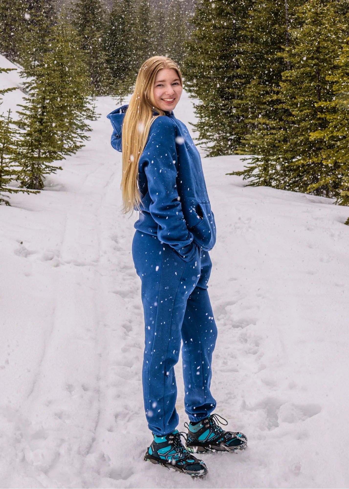Women's Everly Hoodie in Dusty Blue worn with matching sweatpants in a snowy mountain setting.