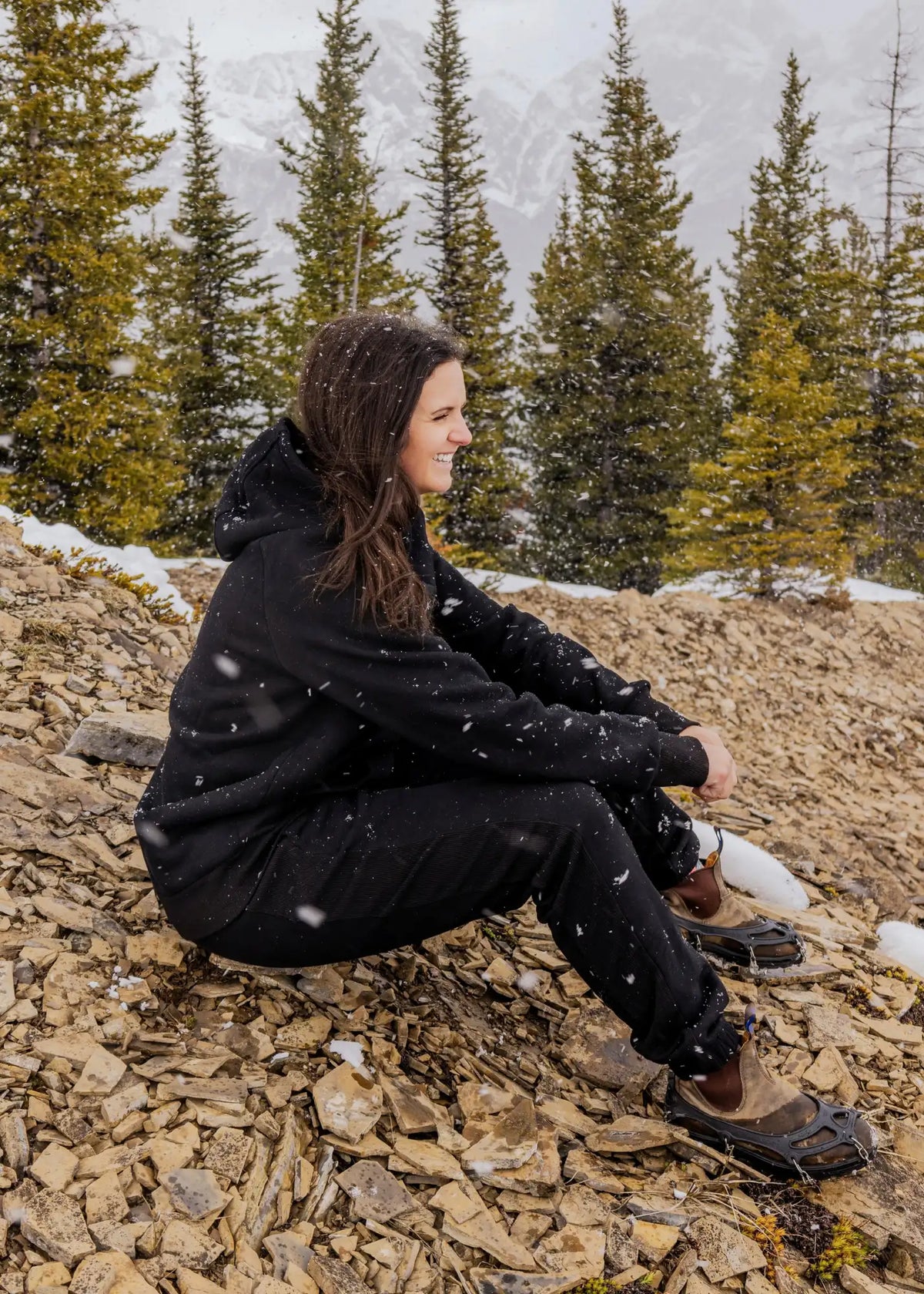 Women's Everly Hoodie in Midnight Black worn with matching sweatpants in a snowy mountain setting.