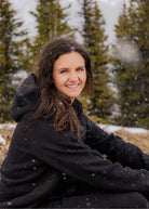 Women's Everly Hoodie in Midnight Black worn outdoors in falling snow.