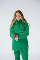Model adjusting the sleeve of a green Nexarina Indy snow jacket