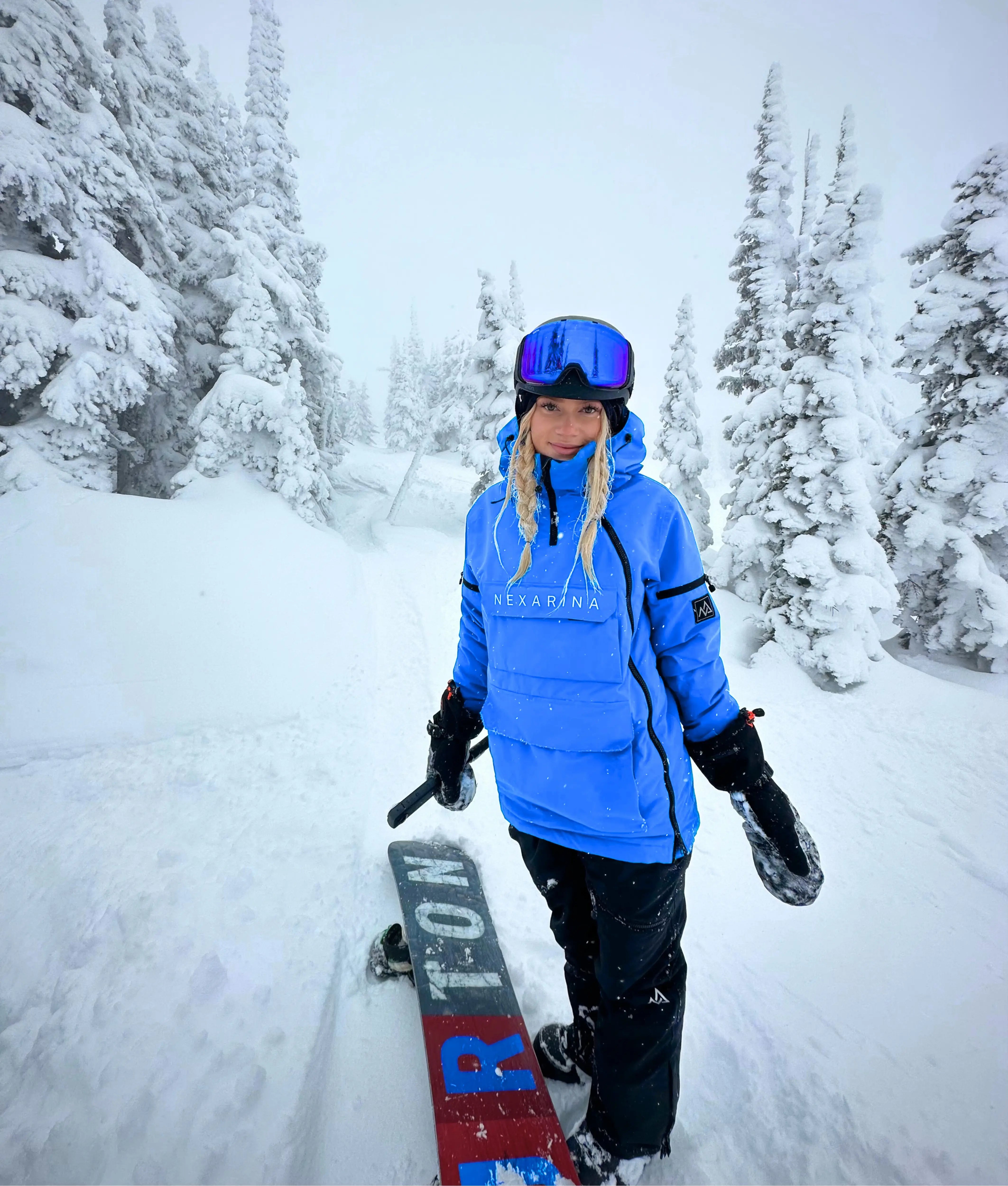 Woman snowboarding in Nexarina Indy Jacket - Arctic Blue waterproof outerwear.