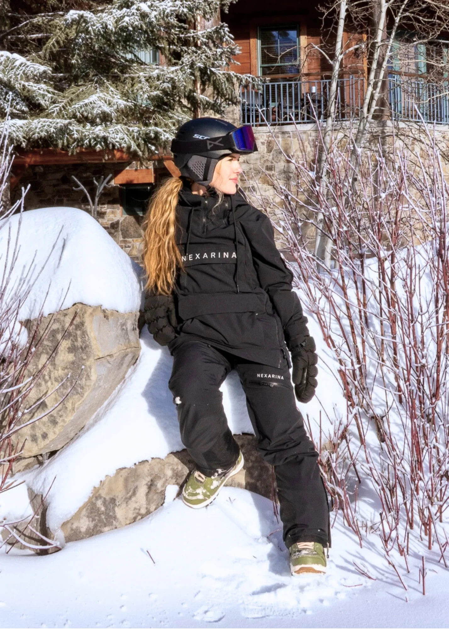 Nexarina Avani women's black snowboard pants rider sitting in powder snow