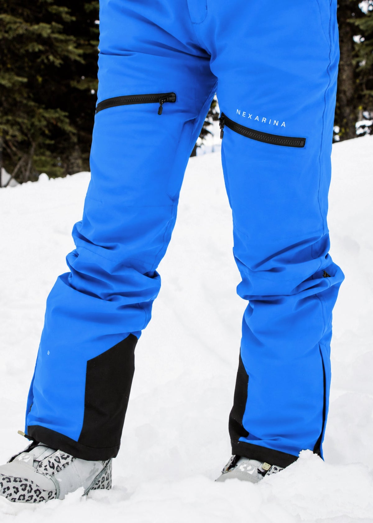 Close-up of Nexarina Avani Arctic Blue snow pants featuring the adjustable waist belt, zippered thigh pockets and Nexarina logo.