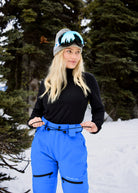 Woman wearing Nexarina Avani Arctic Blue women's snow pants while demonstrating the adjustable drawstring waist belt.