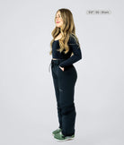 Short women wearing black avani snow pants showing side profile