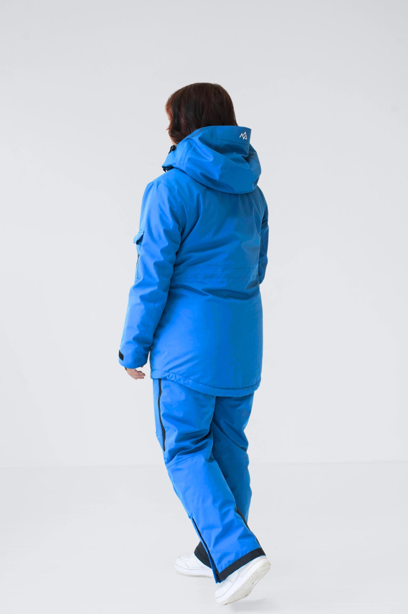  A model wears blue snow pants and jacket, showing a tailored fit, waterproof fabric, and reinforced seams.