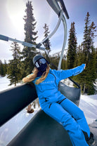 A snowboarder lounges on a ski lift in blue Avani snow pants, built for durability, comfort, and weather resistance.