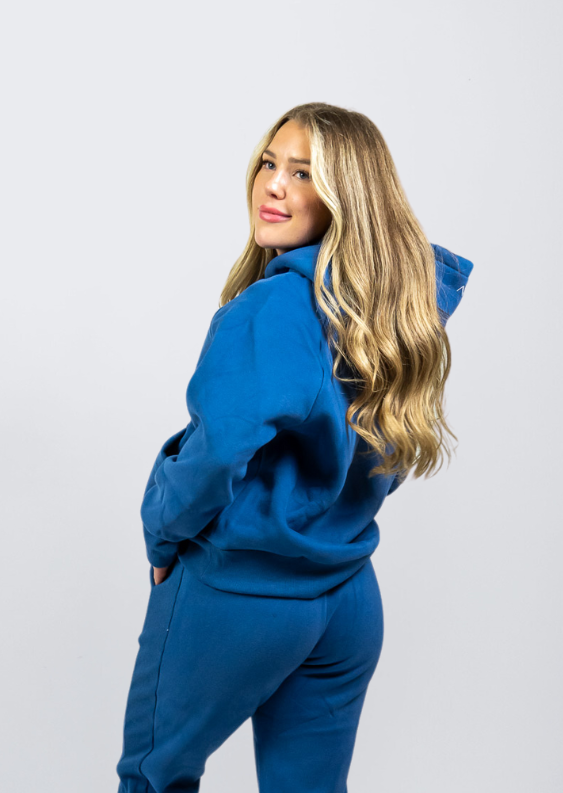 Woman wearing Nexarina Dusty Blue Hoodie smiling and looking back.