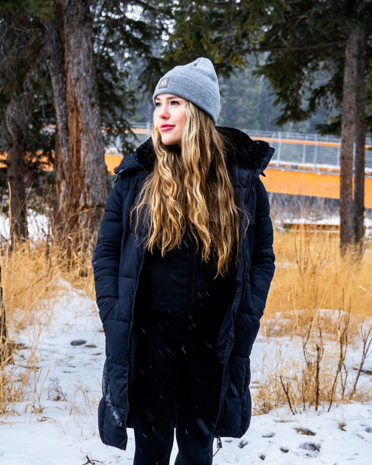 Full-body view wearing grey Emery Beanie in snowy setting