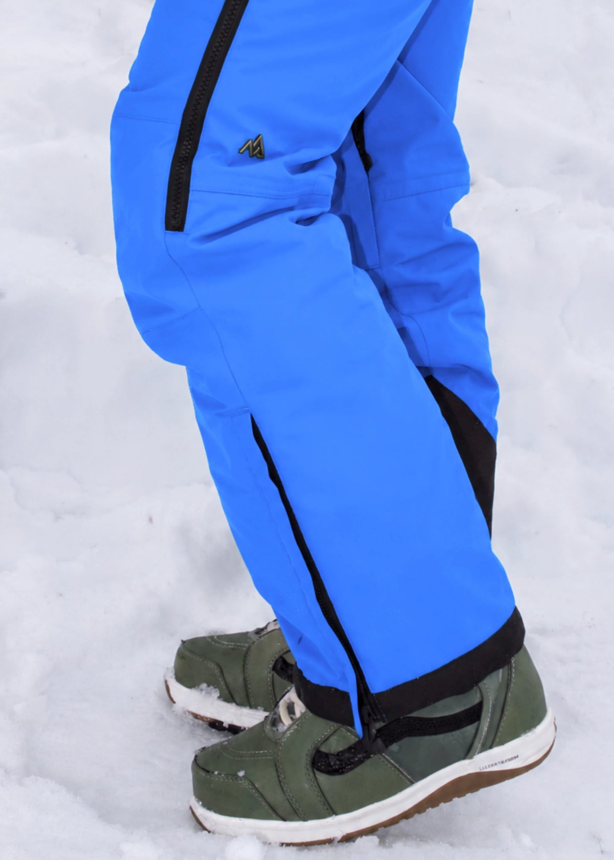 Side view of Nexarina Everette Arctic Blue insulated snow bibs showing the articulated knee design and boot fit.