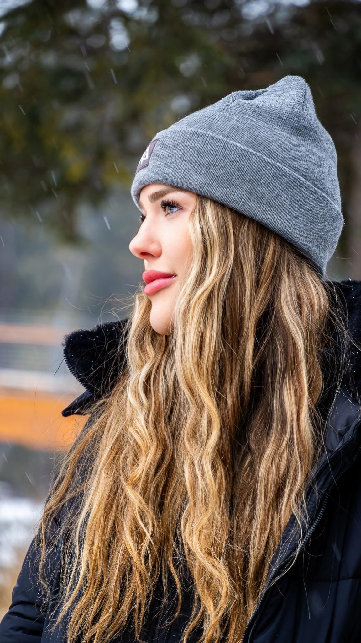 Woman in a grey Nexarina beanie looking off to the side.