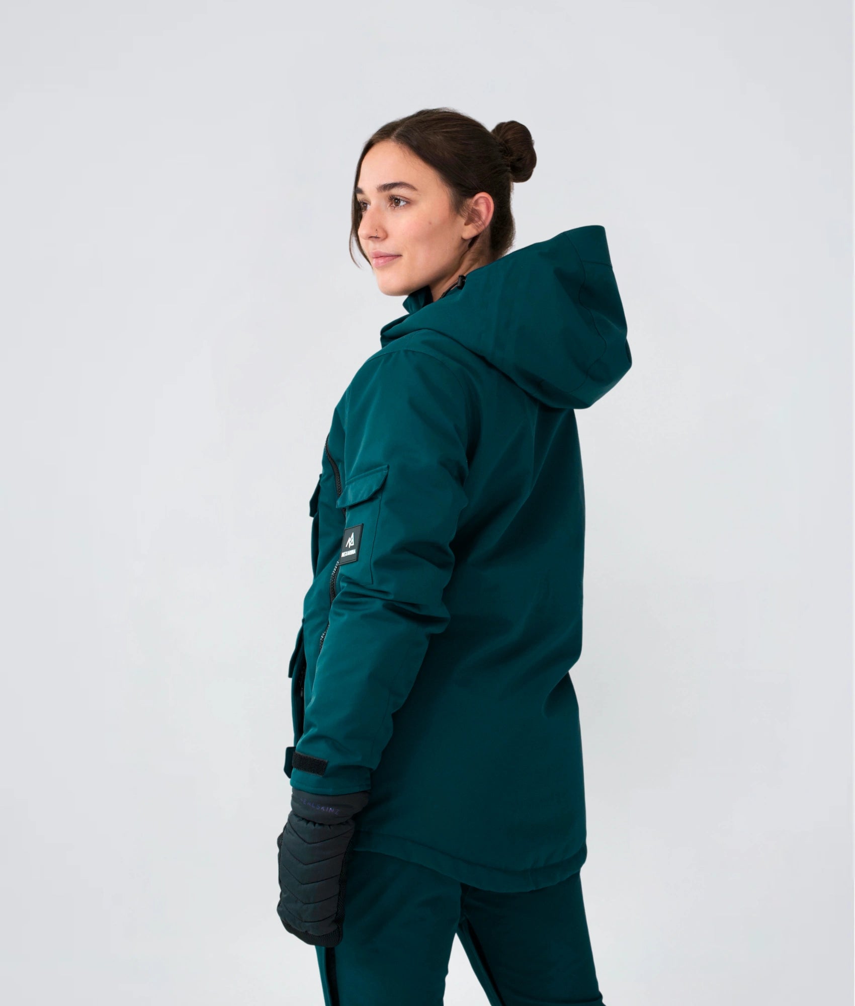 Back view of woman wearing Nexarina Indy snow jacket in emerald green, studio shot