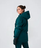 Back view of woman wearing Nexarina Indy snow jacket in emerald green, studio shot