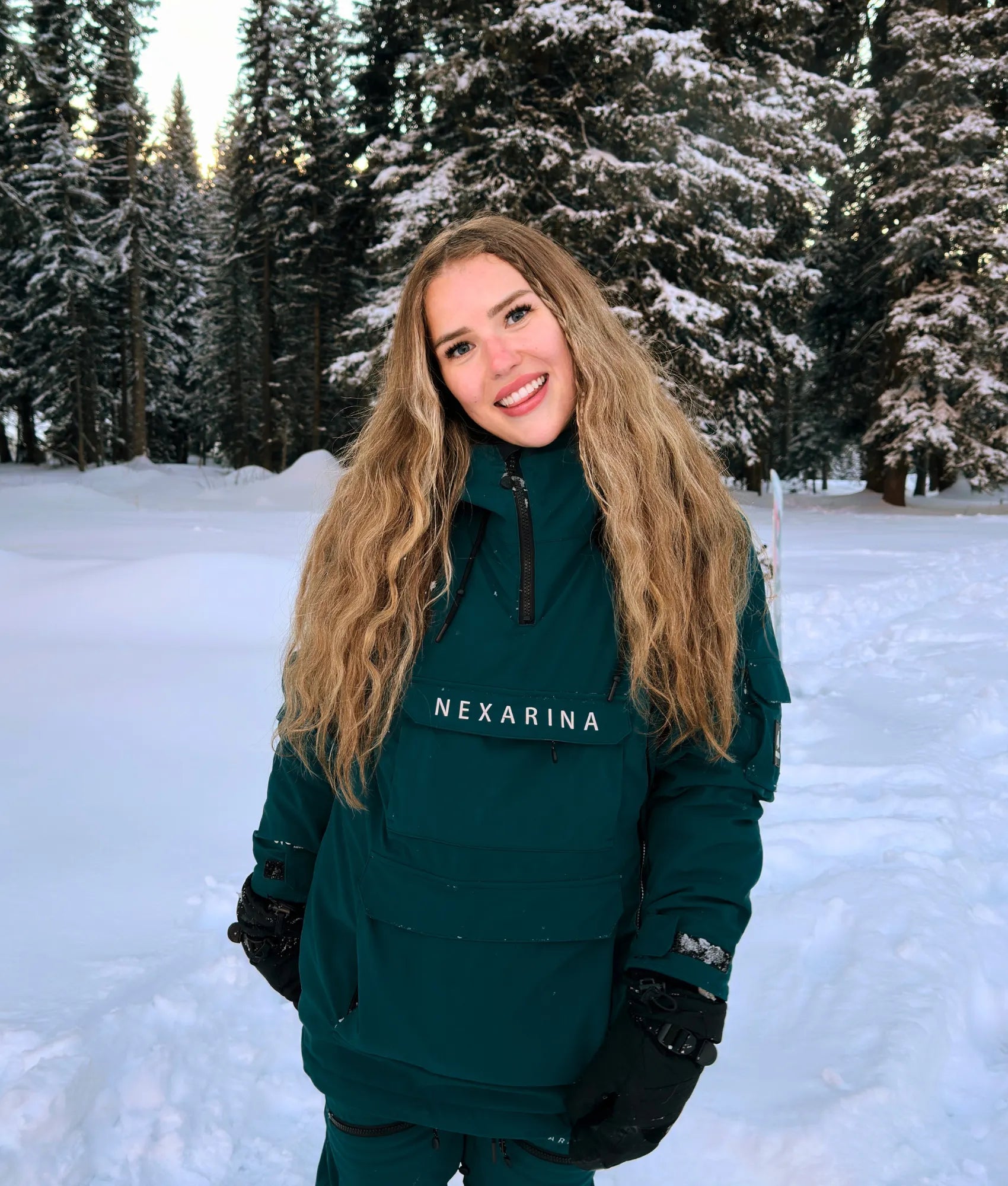 Woman wearing Nexarina Indy snow jacket in emerald green, front view outdoors